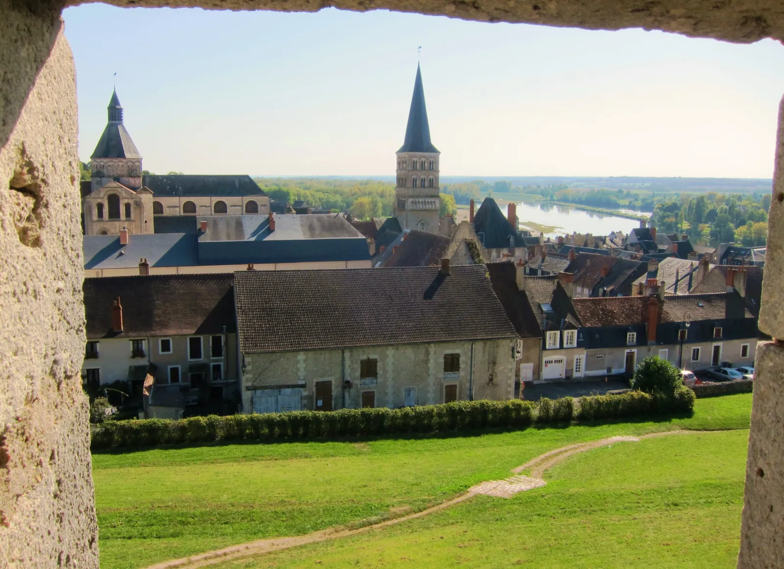 La vieille ville de La Charité-sur-Loire vue par une embrasure des remparts : toits d’ardoise, clochers de l’église Notre-Dame et Loire au loin