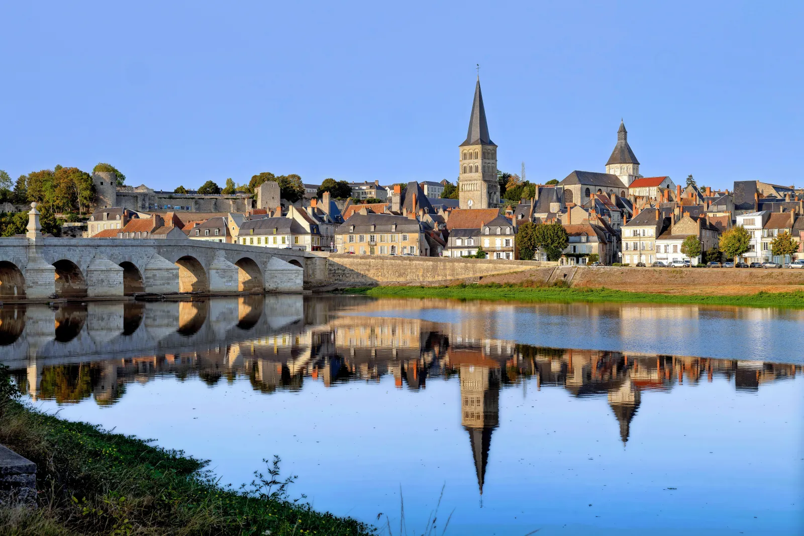 La Charité-sur-Loire vue de la rive gauche : le pont de pierre, les maisons des quais et les clochers de l’église Notre-Dame, qui se reflètent dans la Loire